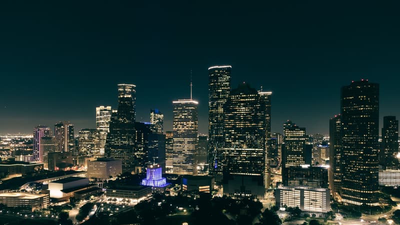 城市中心区夜景俯瞰，写字楼群灯火与高架车流，示意跨国企业全球采购平台的部署